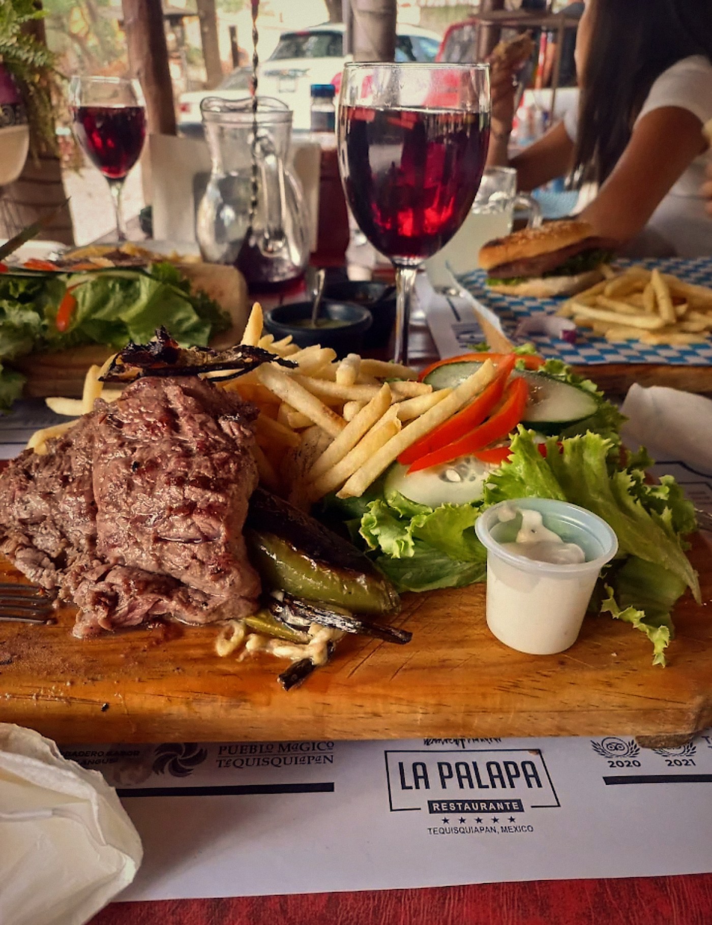 Corte servido en tabla de madera con papas, ensalada y chiles toreados